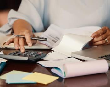 Person sits at a desk calculating bills