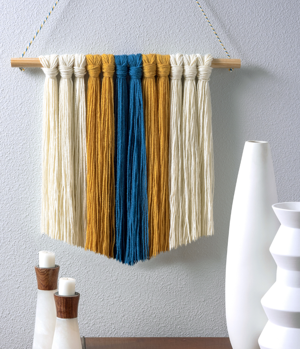 picture of different collored yarn tied on a dowel rod to create a decorative wall hanging
