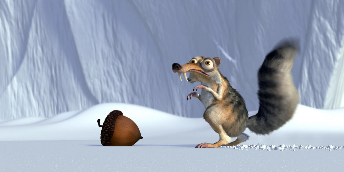 Squirrel next to an acorn in the snow