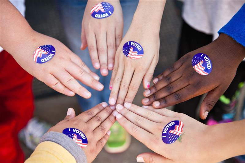 hands with voting stickers