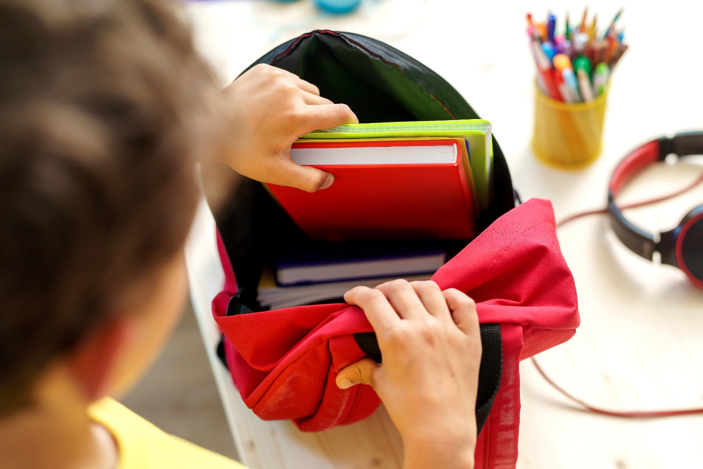 Student putting books into a backpack