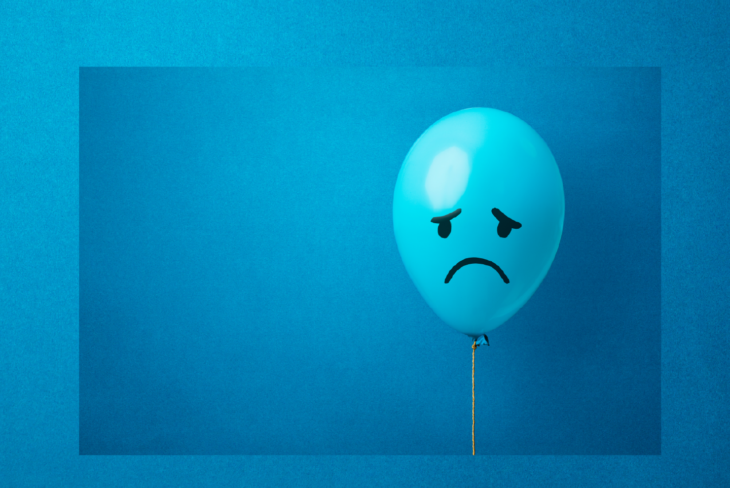 Blue balloon with a sad frowning face on a blue background