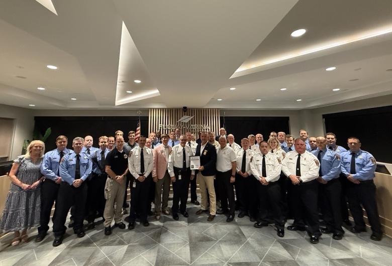 Fire department staff stand with certification plaque