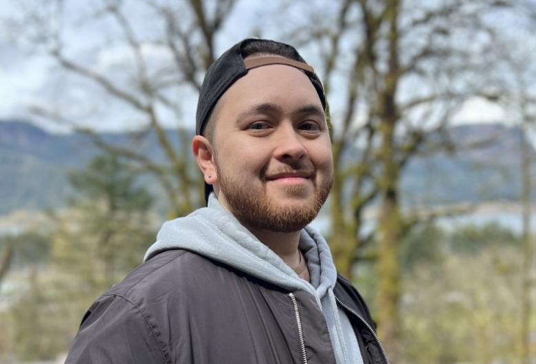 smiling man stands in wooded area