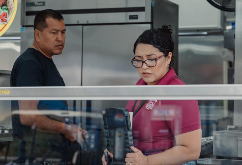 inspector looks at food holding area while restaurant worker looks on