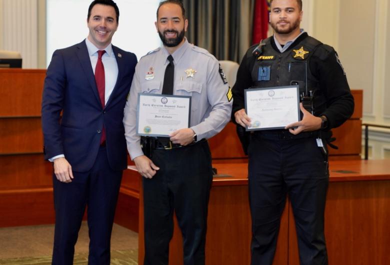 NC Attorney General Jeff Jackson poses with Sergeant Collado and Deputy Garcia holding their Dogwood awards.