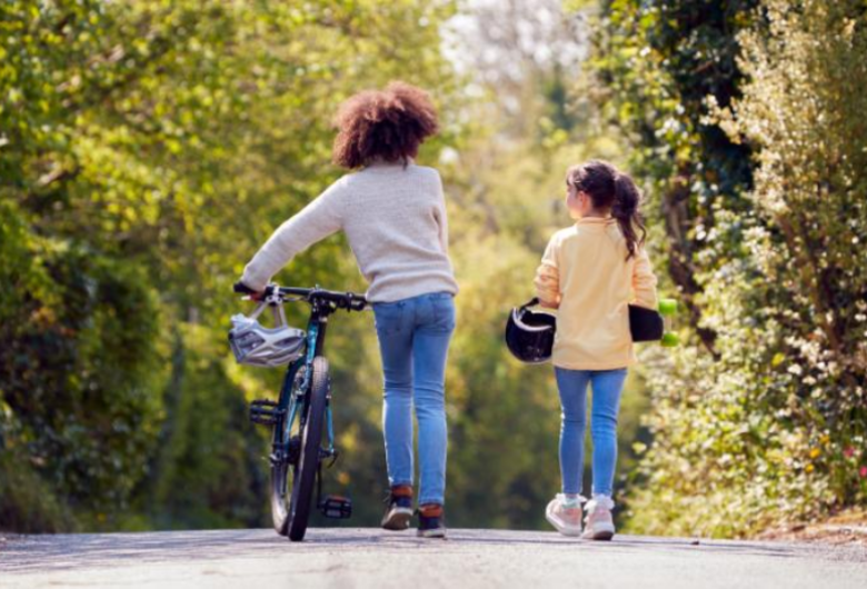 Parent and child walking bikes down a road