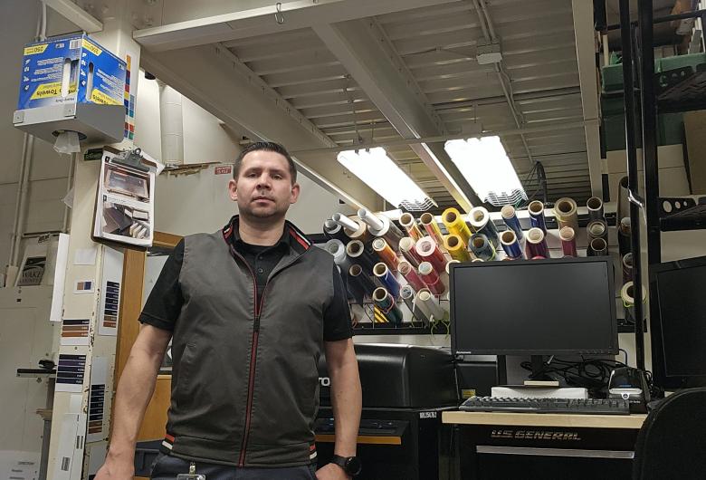 A man standing in a sign production workspace.