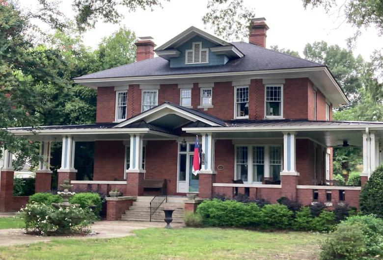 Historic two-story brick house with a large covered porch and landscaped yard in Zebulon.
