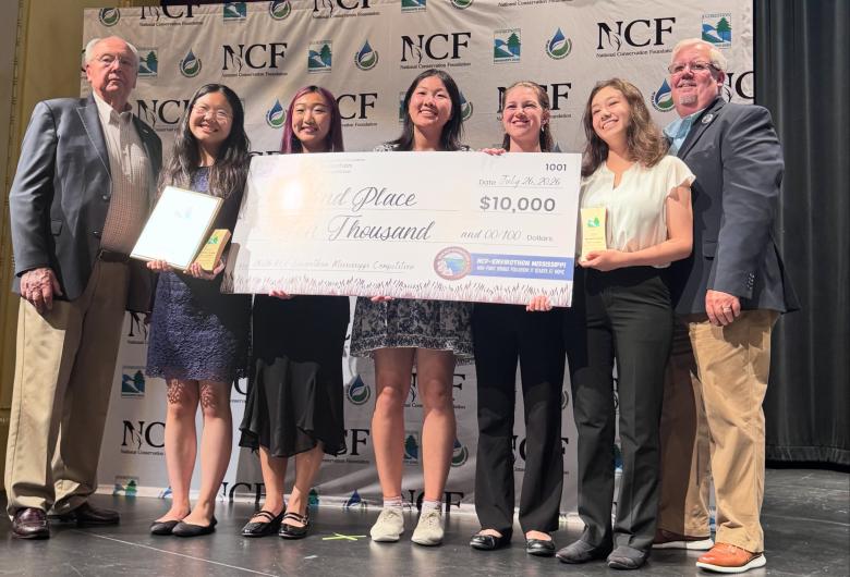 Wake County Envirothon students accept a second-place national award while holding a ceremonial $10,000 prize check on stage.