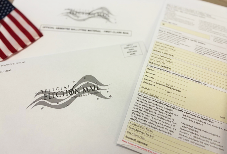 Close-up of an absentee ballot packet with an official election mail envelope and voting forms.
