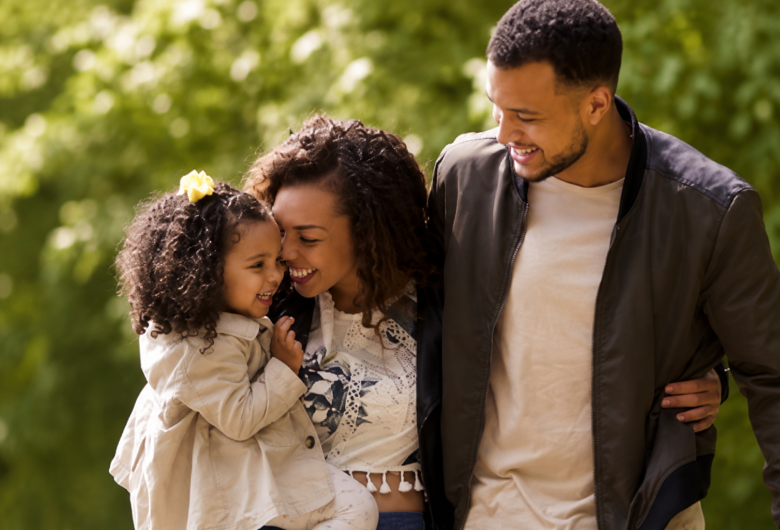 Smiling family of three spending time together outdoors.