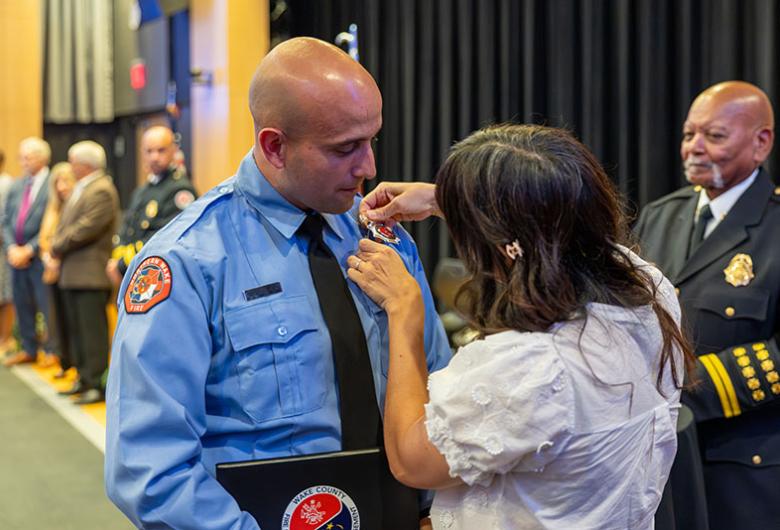 Woman attaches firefighter pin to recent graduate.