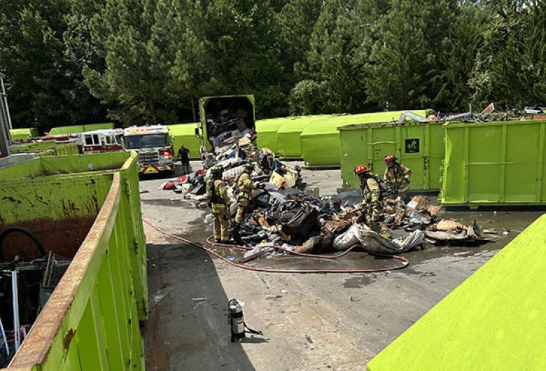 Firefighters responding to a pile of burning debris at a waste facility