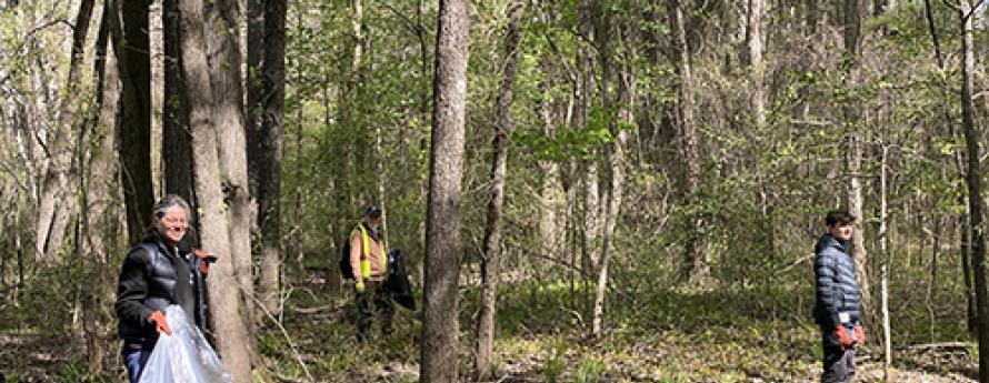 Smiling people pick up trash in the woods