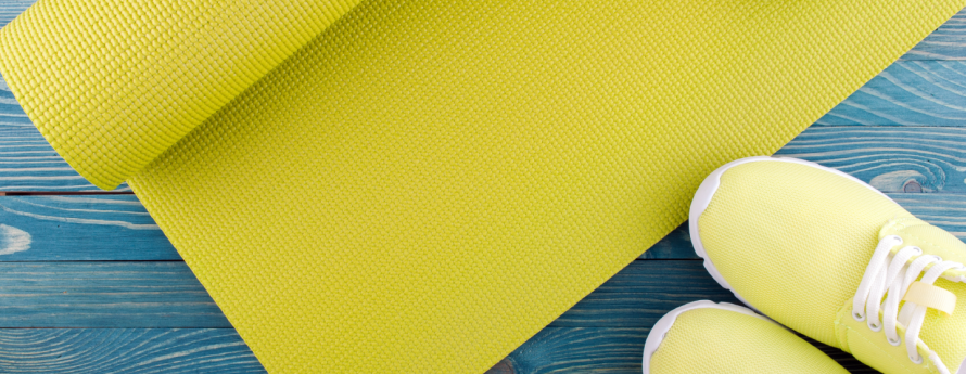 Image of a yellow yoga mat and sneakers on a blue painted wooden floor