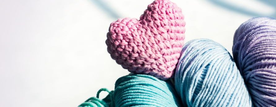 skeins of colored yarn with a crocheted heart no text