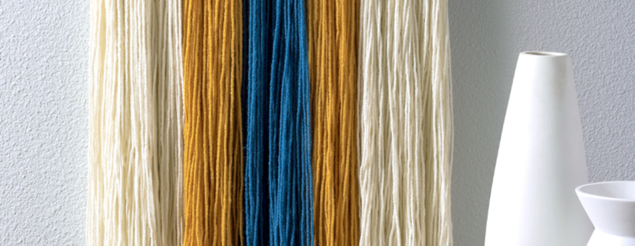 picture of different collored yarn tied on a dowel rod to create a decorative wall hanging