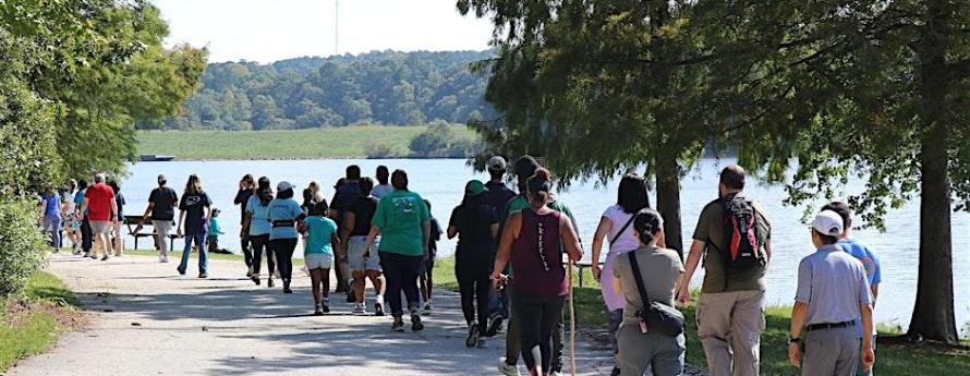 people walking down a path beside a lake