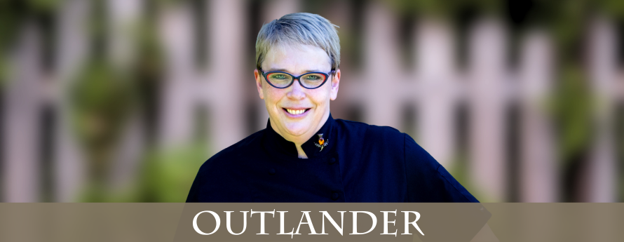 woman with short hair and black glasses, wearing a black chef's jacket