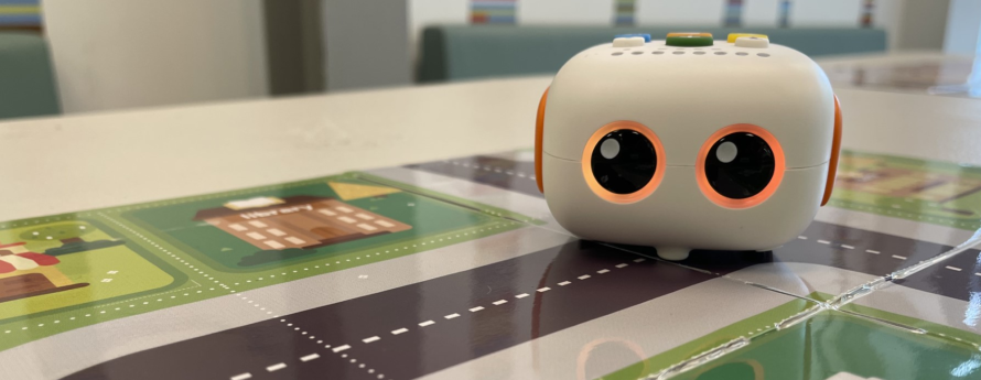 white cube robot with orange glowing eyes on city map