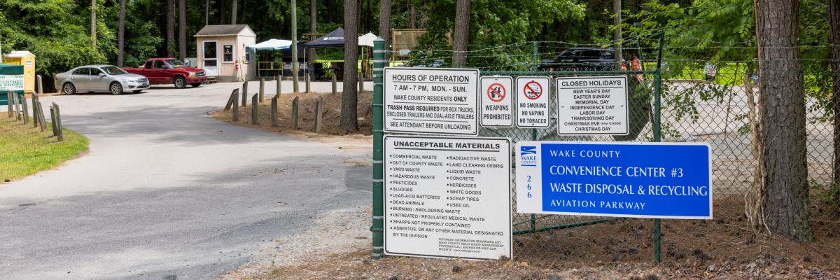 tree-lined entrance to convenience center with vehicles parked inside