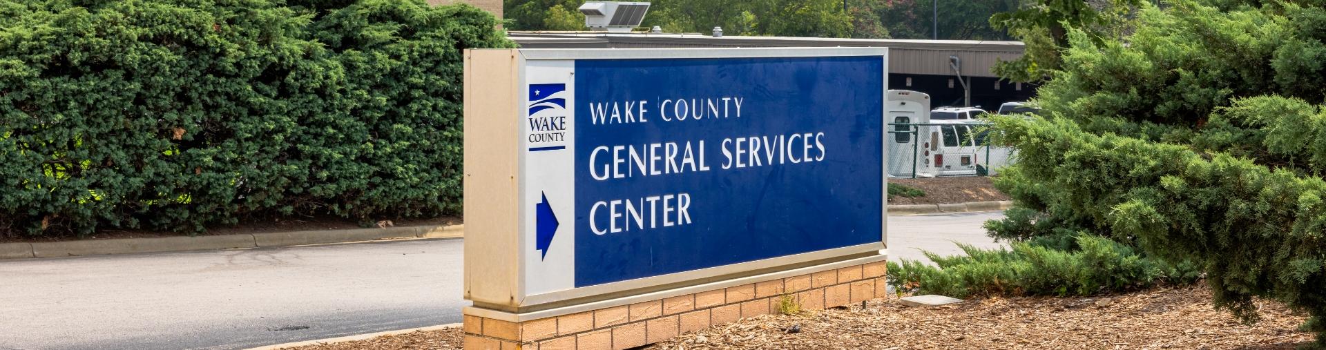 Sign for the Wake County General Services Center beside a roadway and landscaped shrubs.