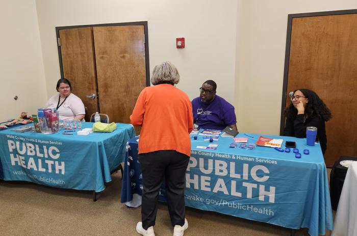 CHWs at community event talk to attendee