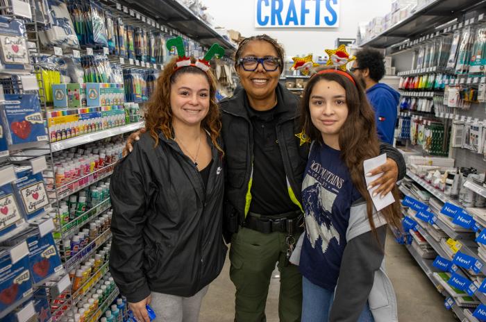 A deputy with her arms around a woman and a young girl in an aisle at Walmart