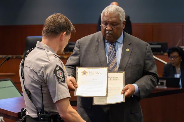 Sheriff Willie Rowe hands a commendation certificate to a deputy
