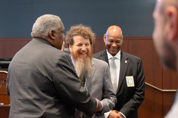 Adam Levy smiles as he shakes Sheriff Willie Rowe's hand. Another deputy can be seen in the background. 