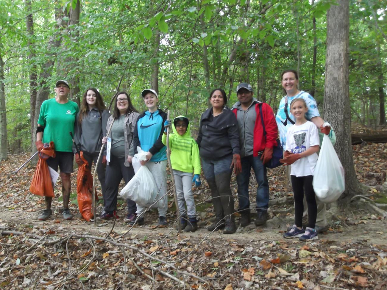 Volunteers holding filled trash bags of litter posing for a picture. 