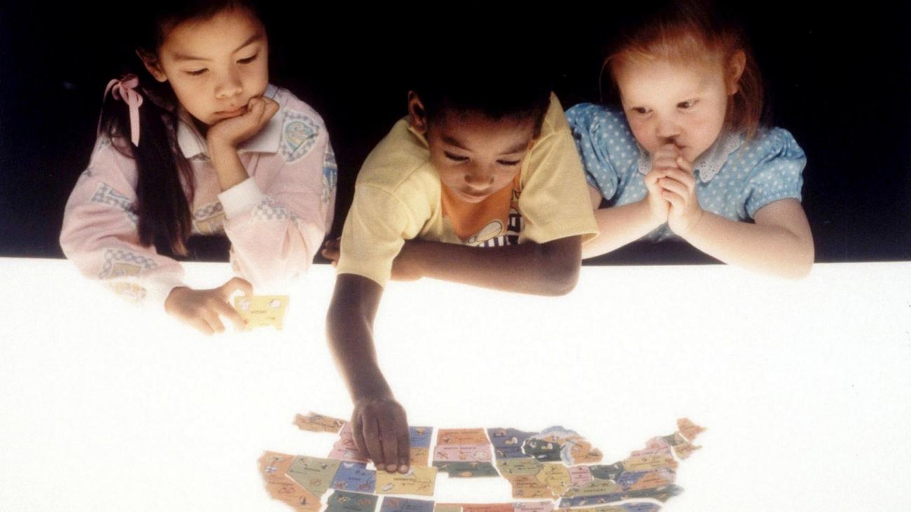 children putting together a puzzle of a map.