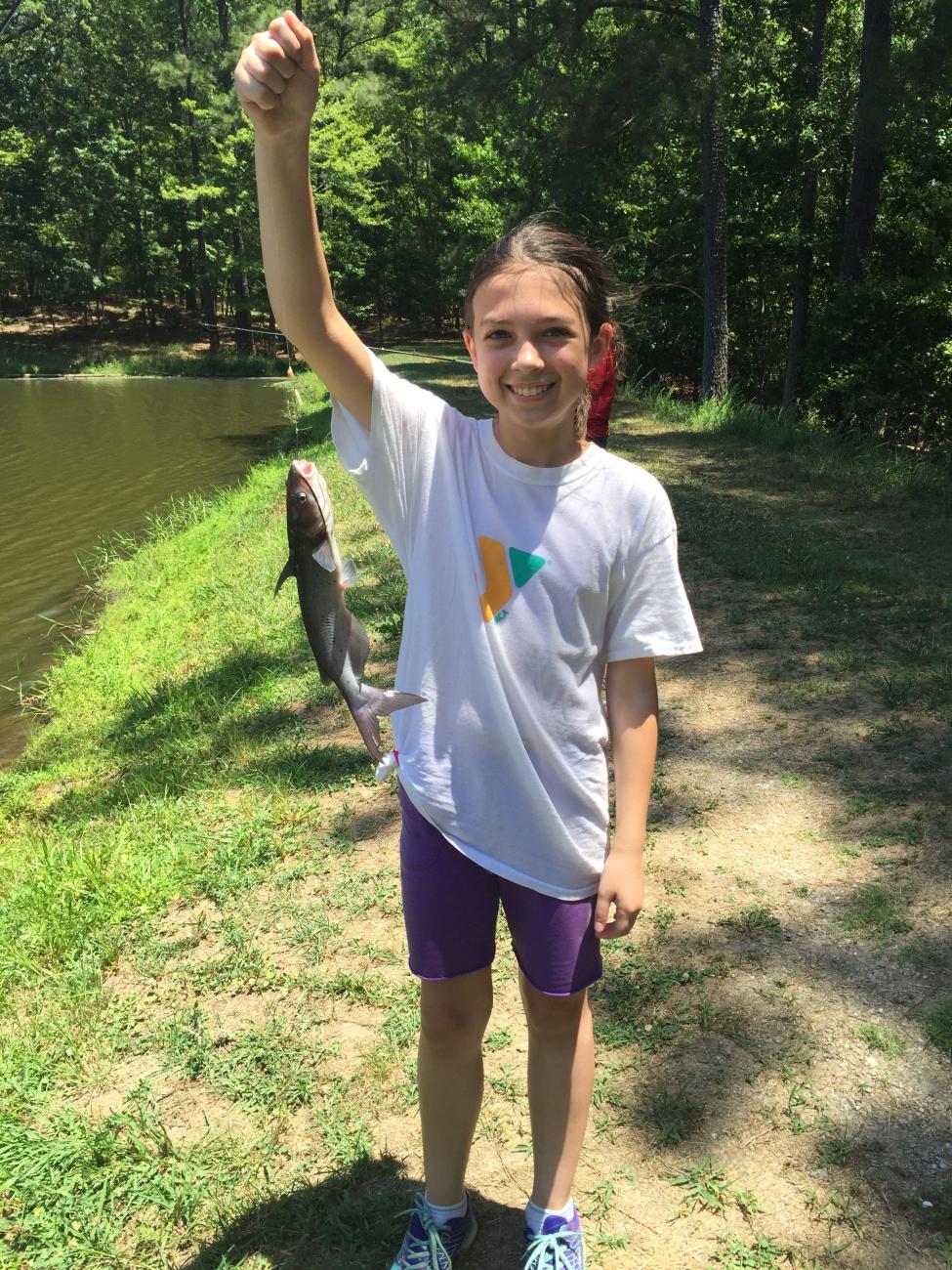 A photo of a female camper holding a catfish she just caught