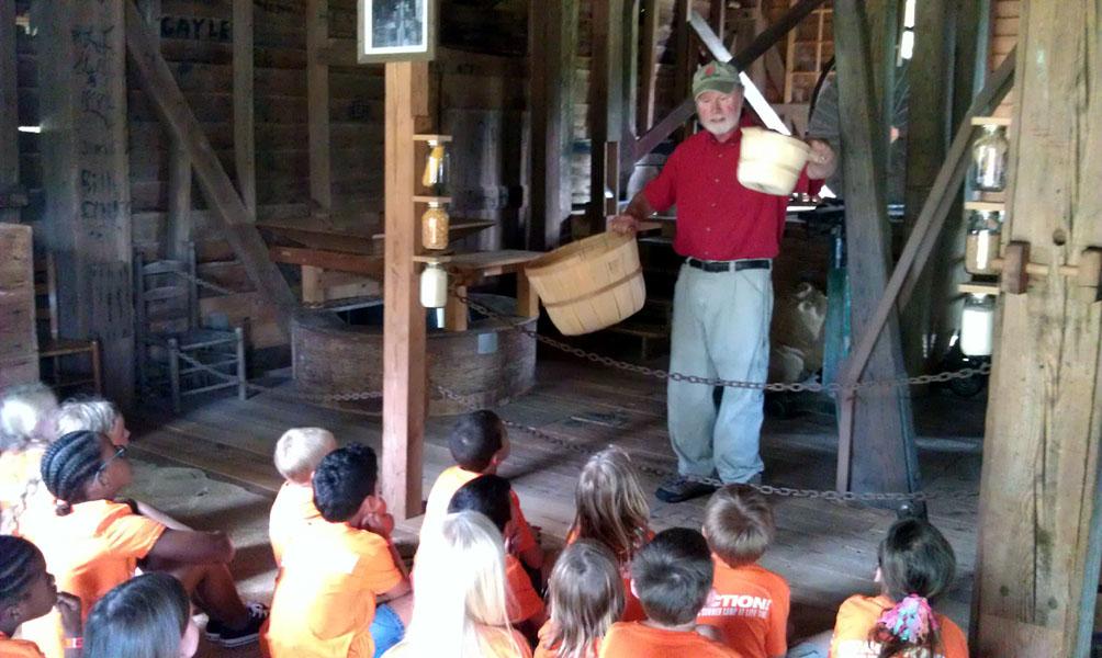 children sit inside of old wooden mill building during tour