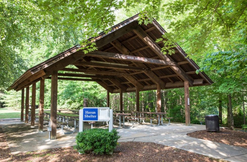 View of parks largest sized wooden picnic shelter with picnic tables 