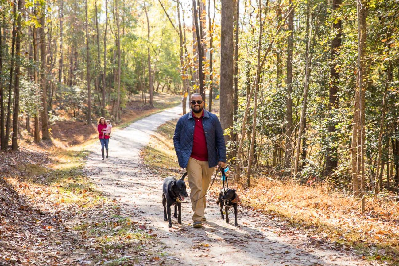 Photo of guests with children and dogs walking down preserve trail