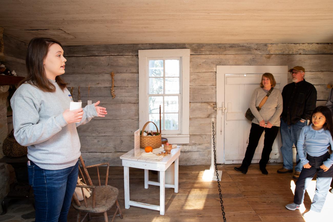 Staff member delivering a public tour to a group of visitors inside the 1825 detached kitchen