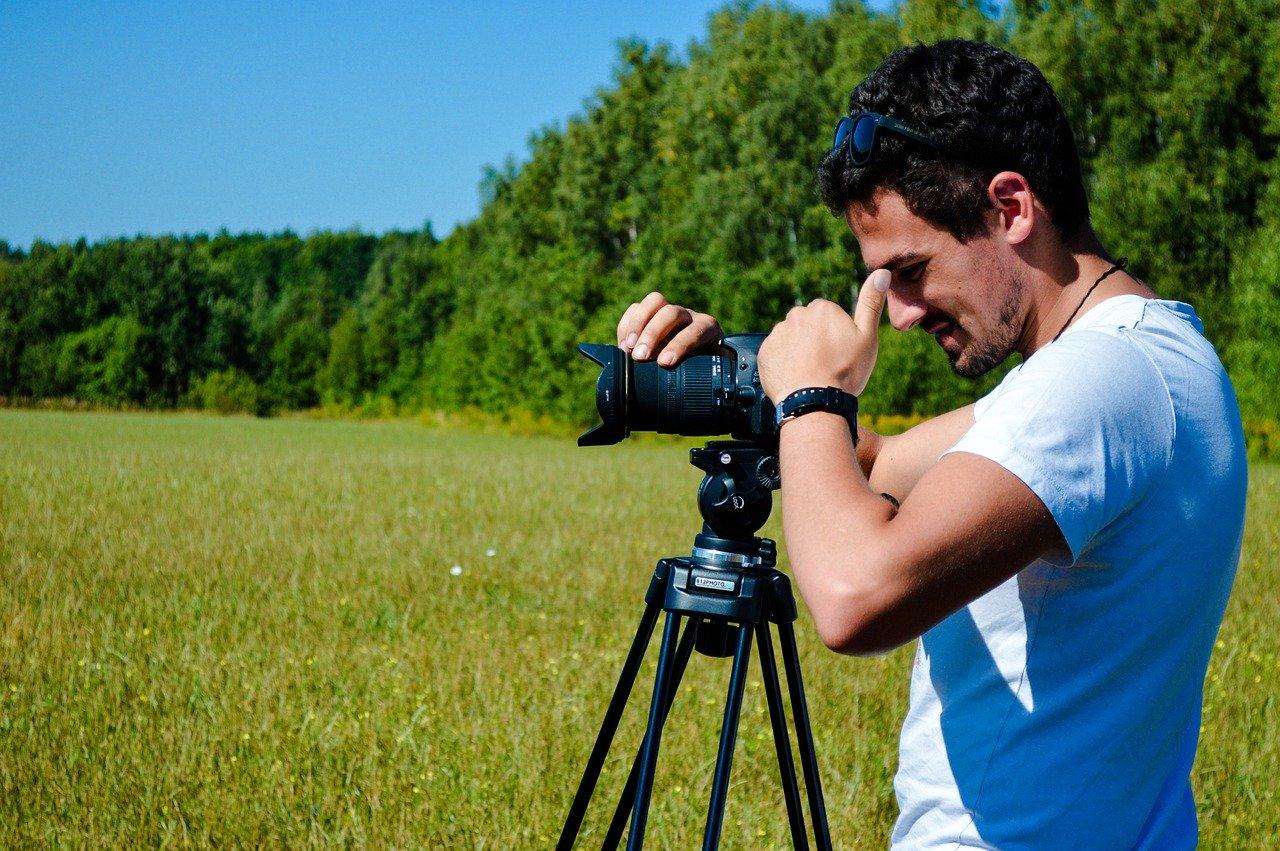 A photographer focusing a camera in the park