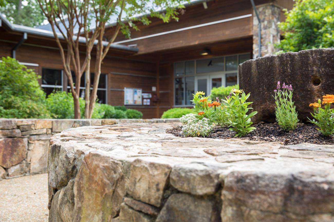 view of stone building with mill stone flower bed in front with paved stone path