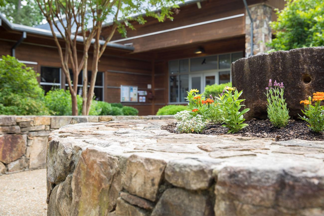 view of stone building with mill stone flower bed in front with paved stone path 