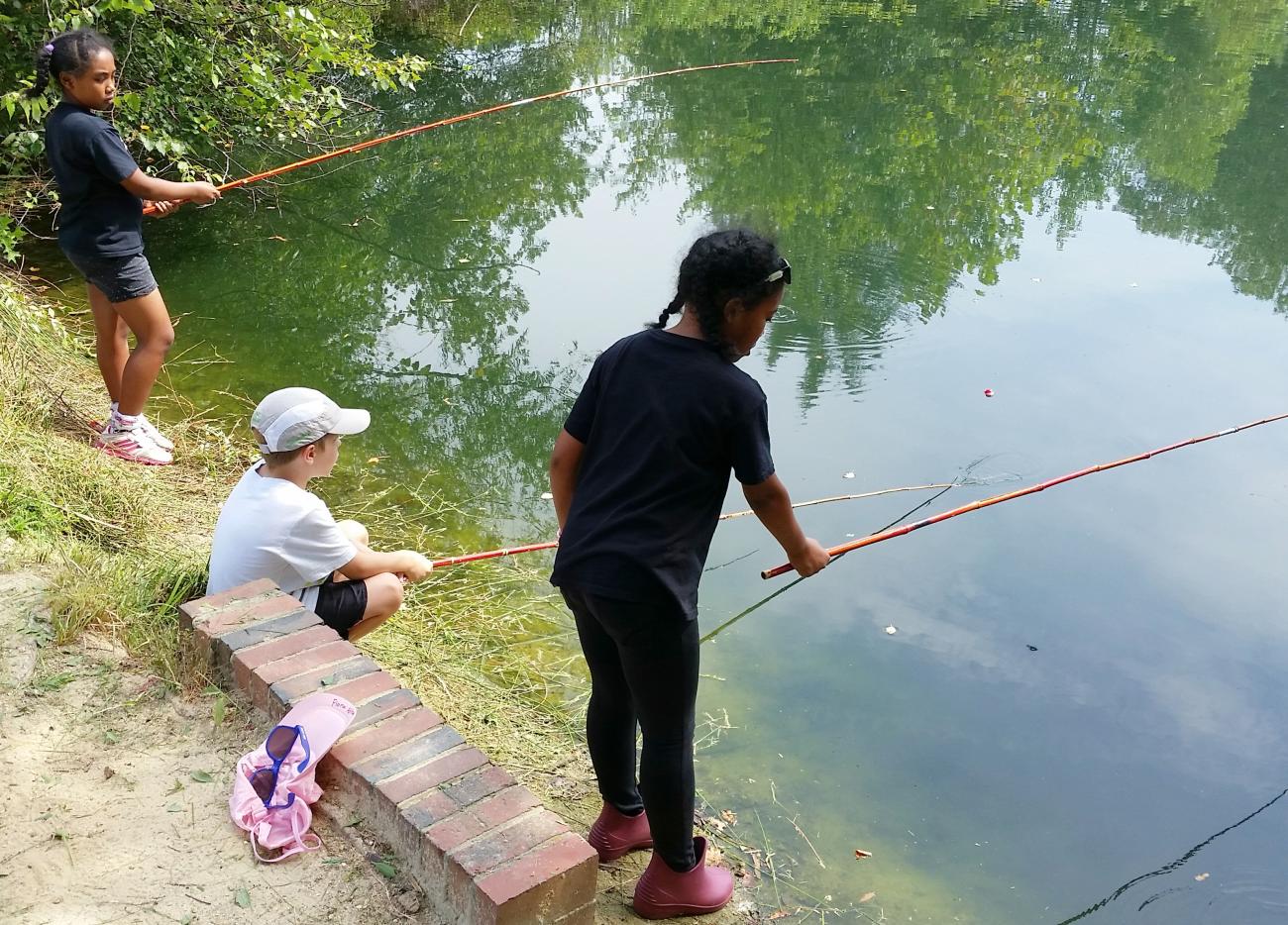 three children fishing with cane poles at the pond at Oak View