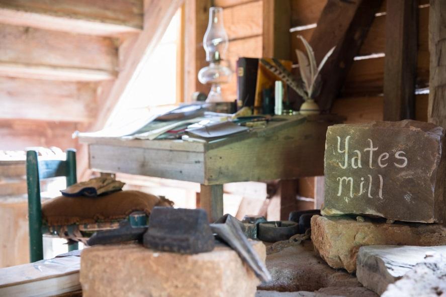 old desk with feather quill and rock that says yates mill inside old mill building