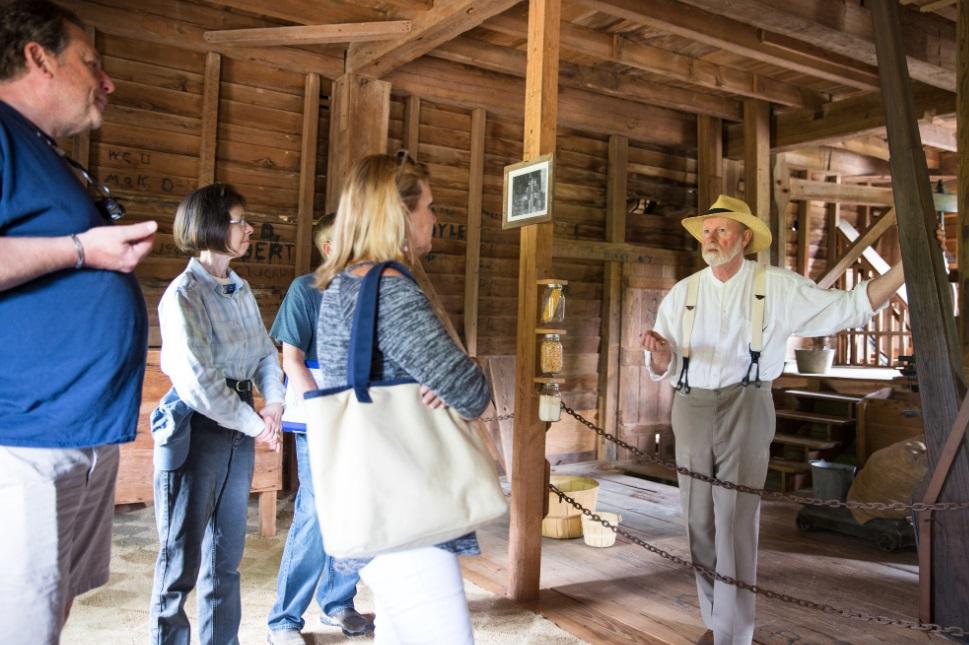 Volunteer speaks with tour participants inside of old mill