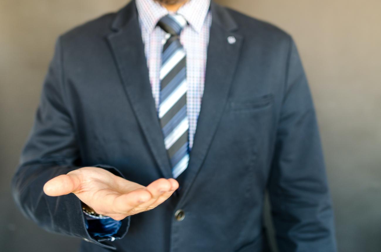 Man in suit holding out his hand.