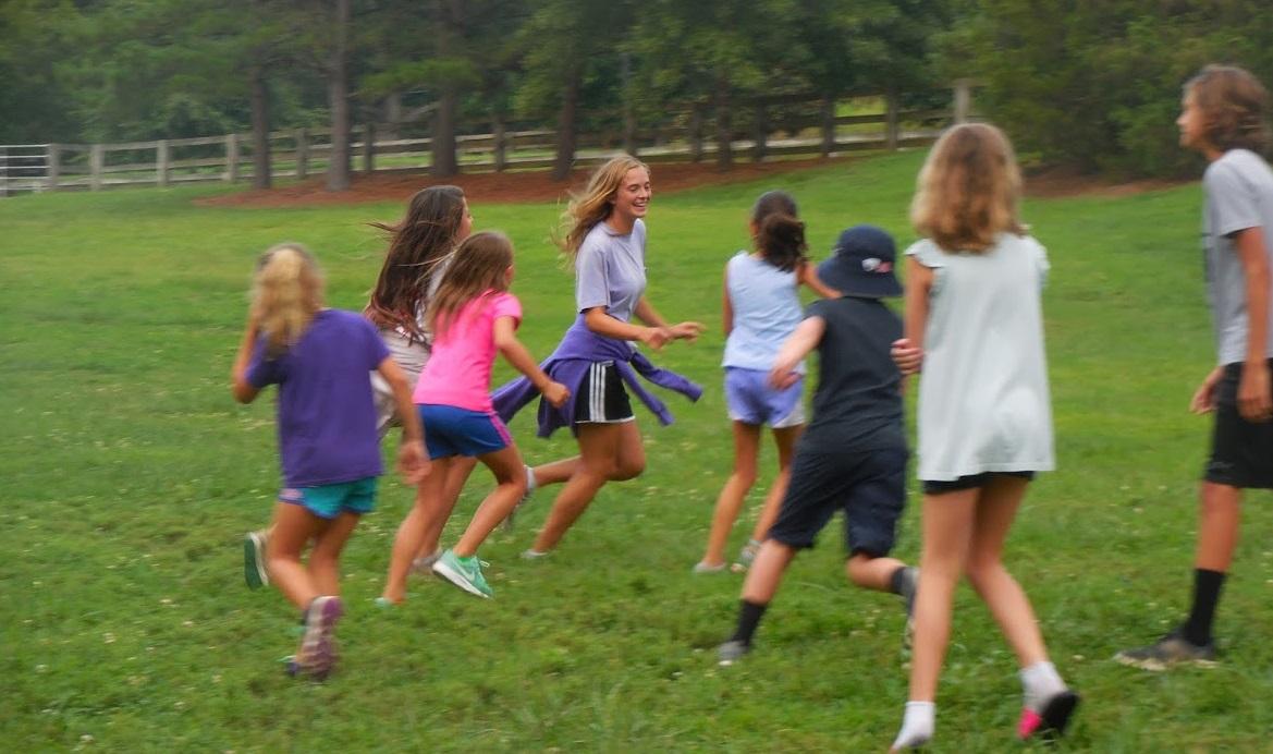 Kids run around in open field playing games