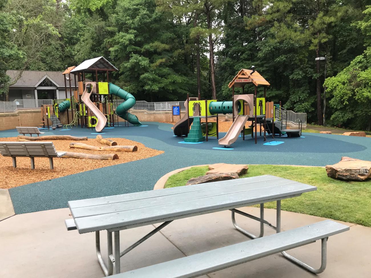 Picnic table in foreground with playground equipment in the back.