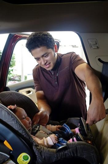 Man fastening infant in a car seat 