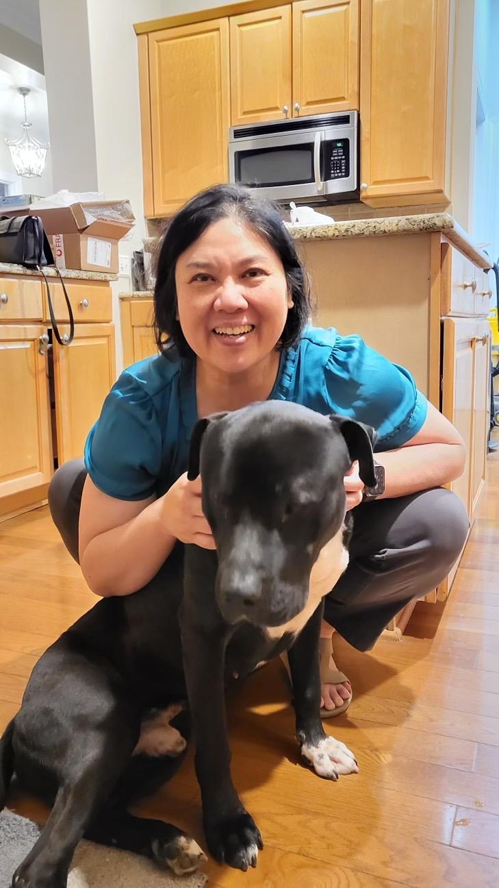 Commissioner Maria Cervania crouches to pose with her adopted dog