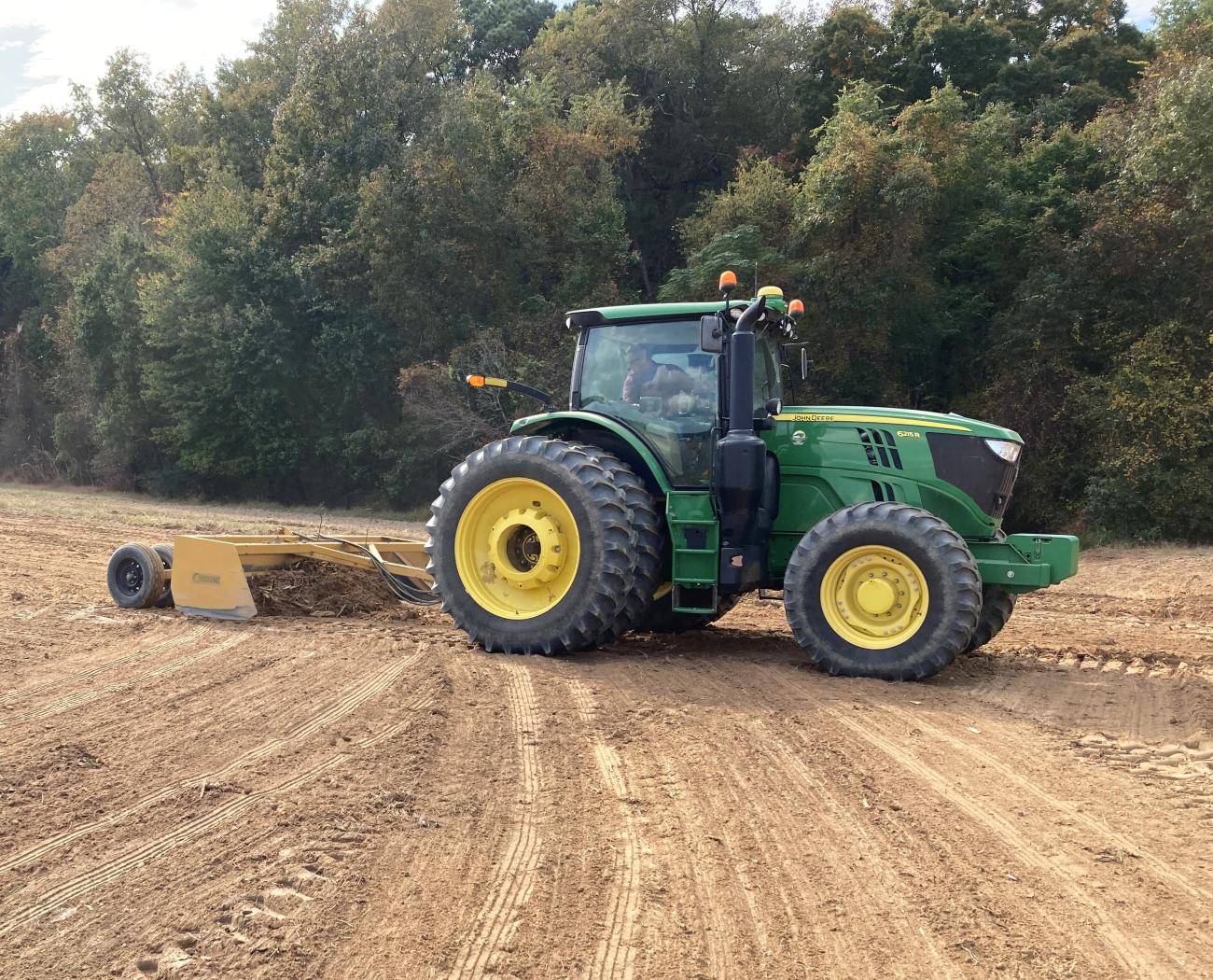 A tractor grading the land during the installation of a grassed waterway.